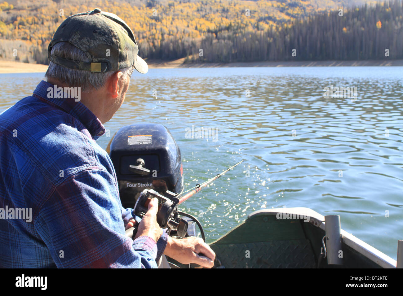 Senior man fishing and trolling from back of small aluminum boat or