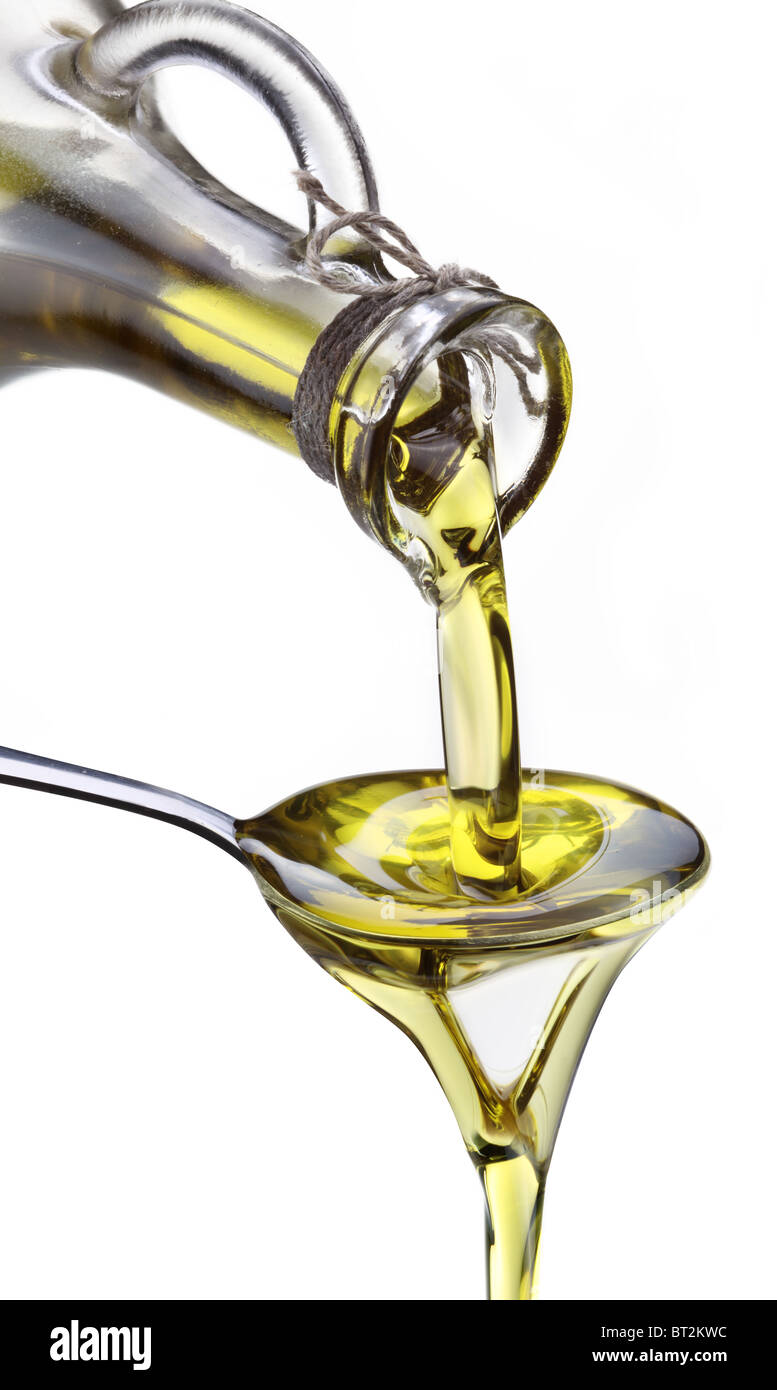 Olive oil flowing on spoon from bottle hires stock photography and