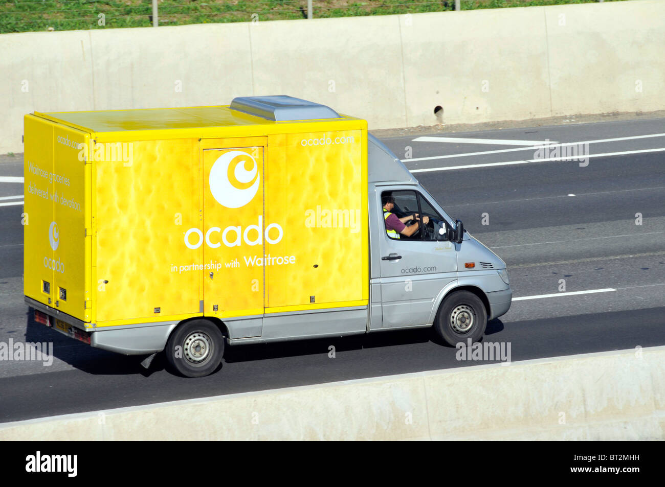 Side & roof aerial view from above looking down yellow Ocado online business grocery food shopping delivery van & logo driver on English UK motorway Stock Photo