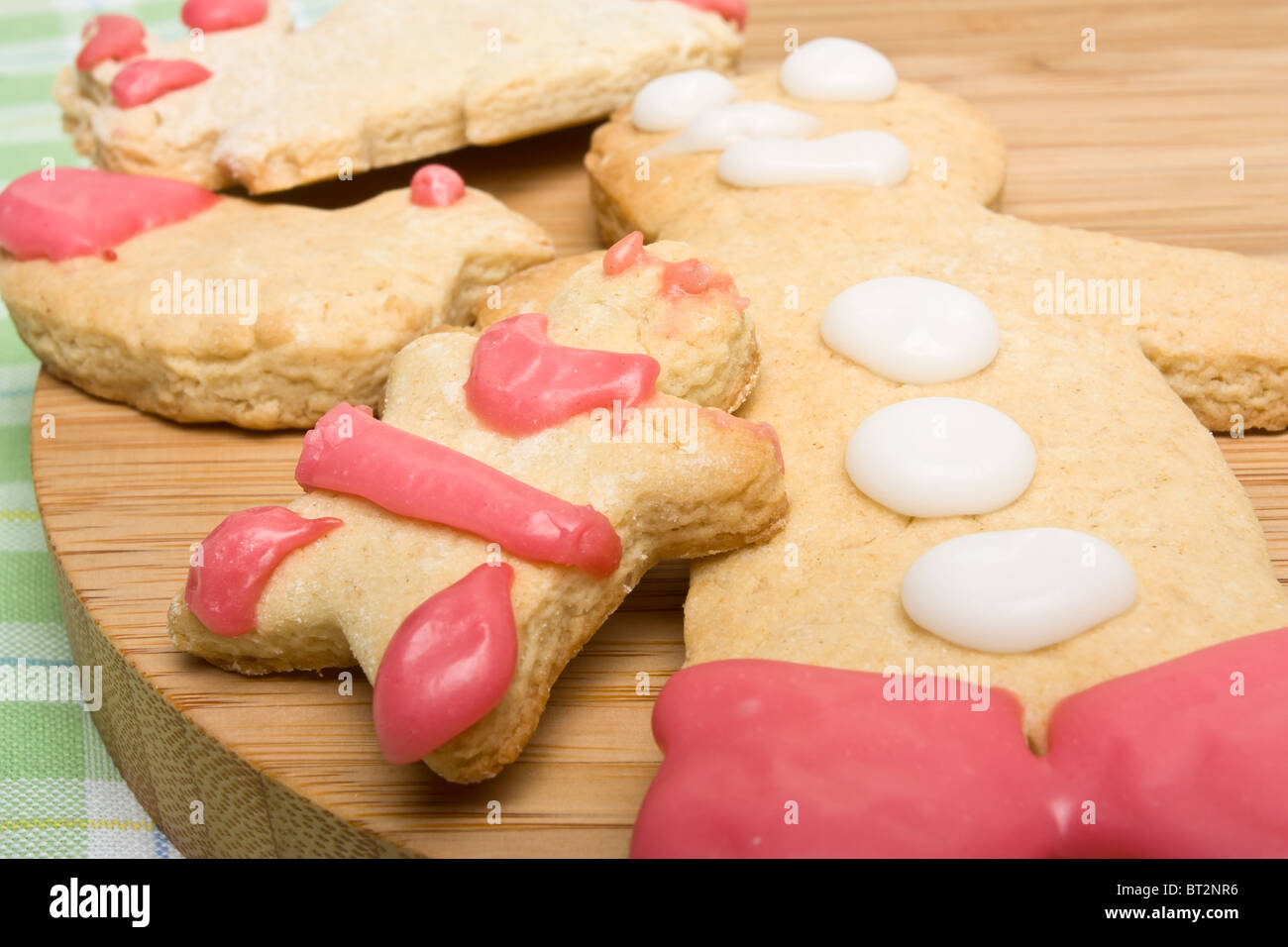 Gingerbread biscuits decorated by child on wooden board from low perspective. Stock Photo