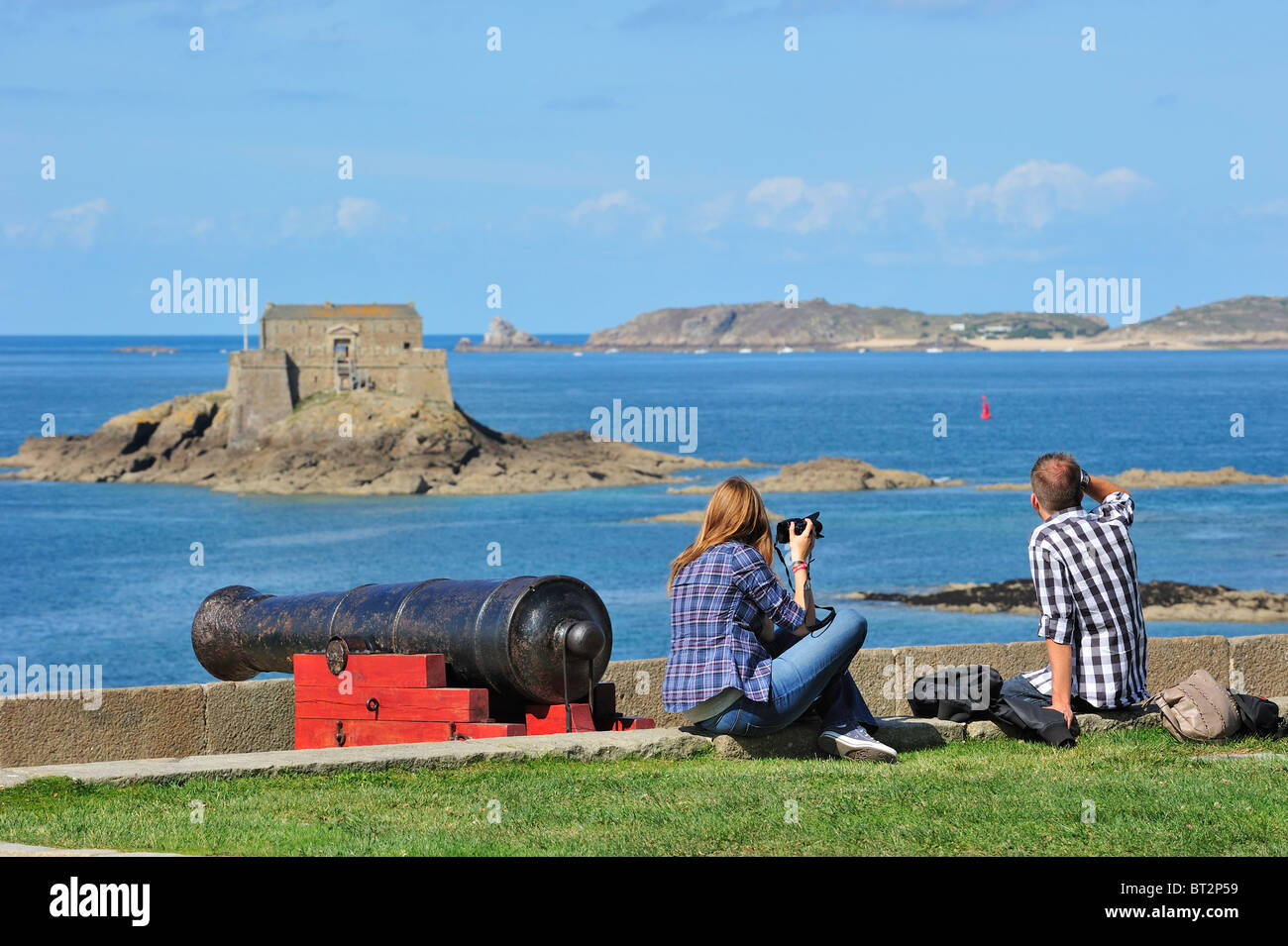 Old cannon at rampart and tourists lookig at fort Petit Bé in the sea at Saint-Malo, Brittany, France Stock Photo