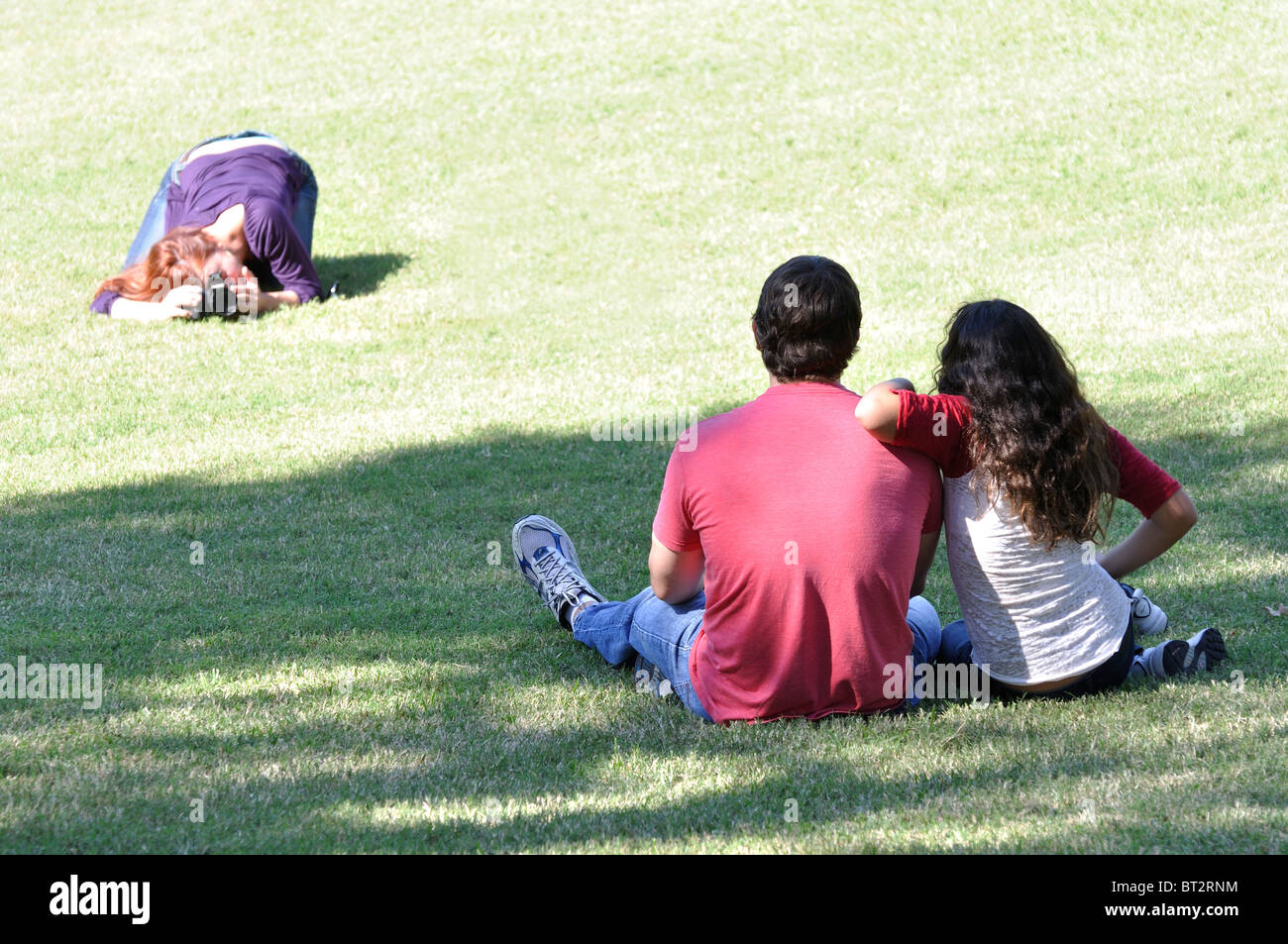 Young couple sitting on grass and being photographed Stock Photo - Alamy