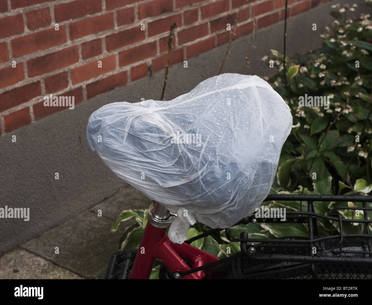 Bicycle saddle with a wet plastic bag over it. Stock Photo