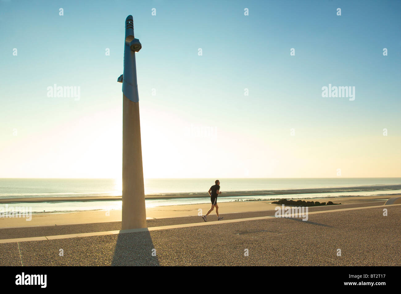 Jogger on Cleveley's promenade as the sun goes down on a hot summer day Stock Photo