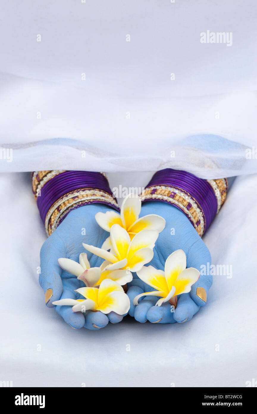 Indian girl with blue hands and bangles holding frangipani flowers Stock Photo