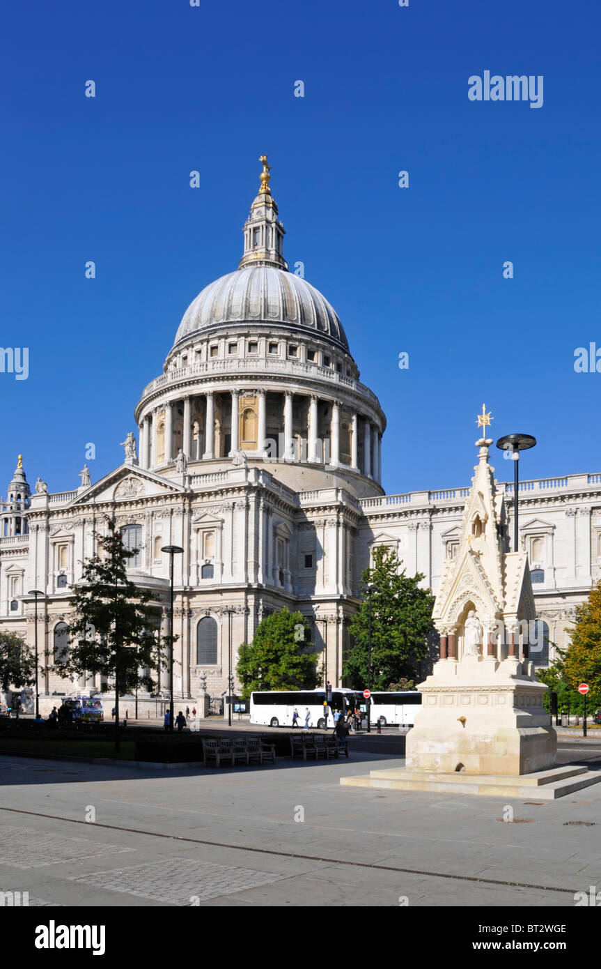 Tourist coaches outside famous historical St Pauls cathedral &  St Lawrence Jewry Memorial Fountain on sunny blue sky day in City of London England UK Stock Photo