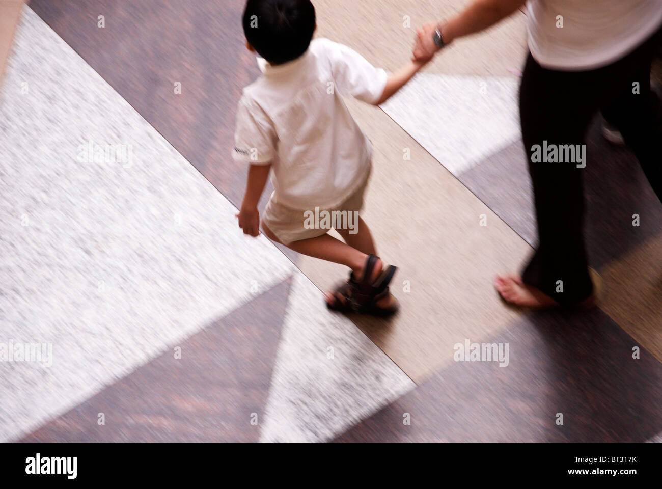 looking down at two people walking in one of the many shopping malls in Singapore Stock Photo
