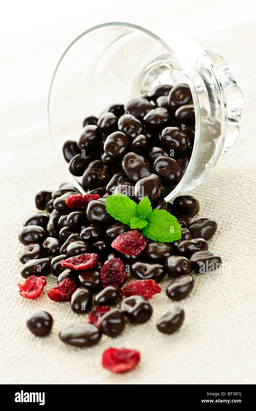 Chocolate covered cranberries spilling from glass dish Stock Photo Alamy