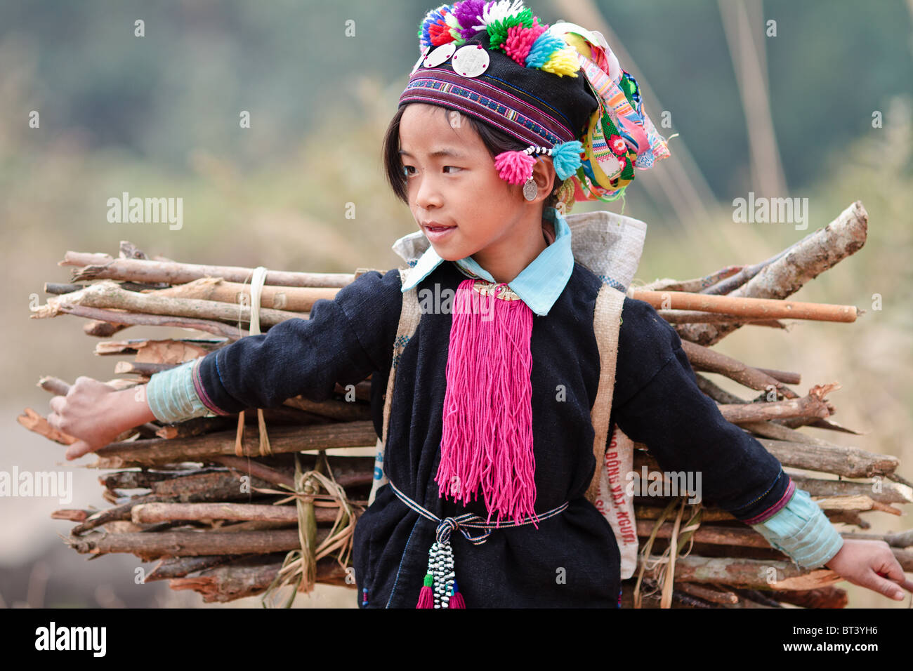Young Black Dzao girl carrying firewood in order to earn money for an ice cream Stock Photo