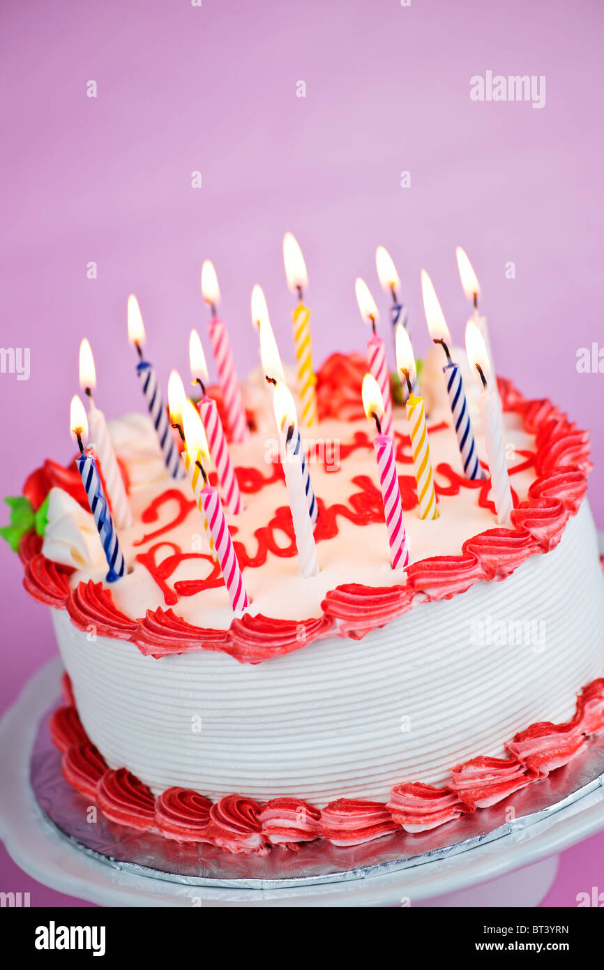 Birthday cake with burning candles on a plate on pink background Stock ...