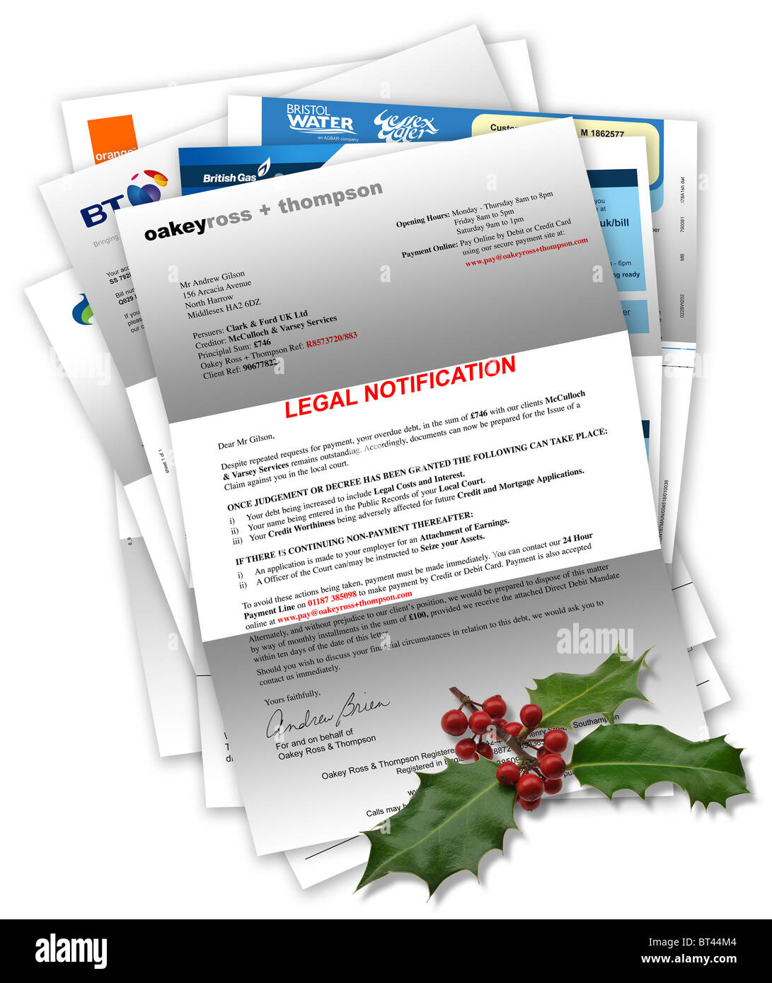 Legal Notification Letter due to unpaid/bad debt with household bills beneath and Christmas holly on top Stock Photo