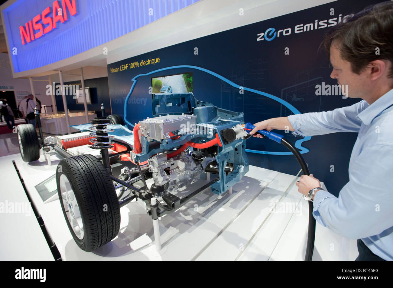 Visitor using plug-in electric charging station for Nissan vehicle at Paris Motor Show 2010 Stock Photo