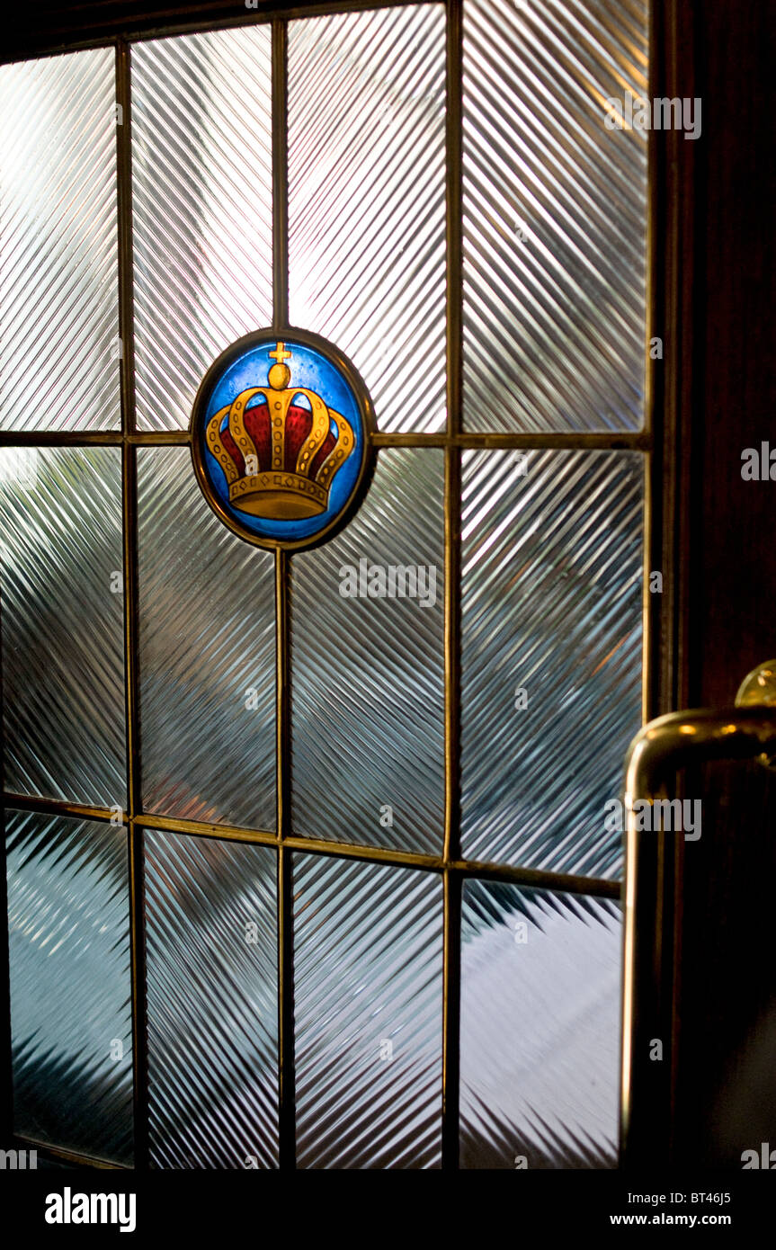 an antic glass door with a gold and red crown in Zurich Switzerland Stock Photo
