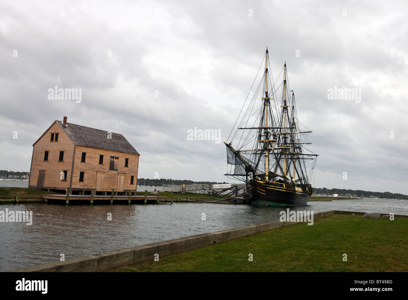 Friendship of Salem docked next to a boarded up saltbox style building, Salem Maritime National Historic Site Stock Photo