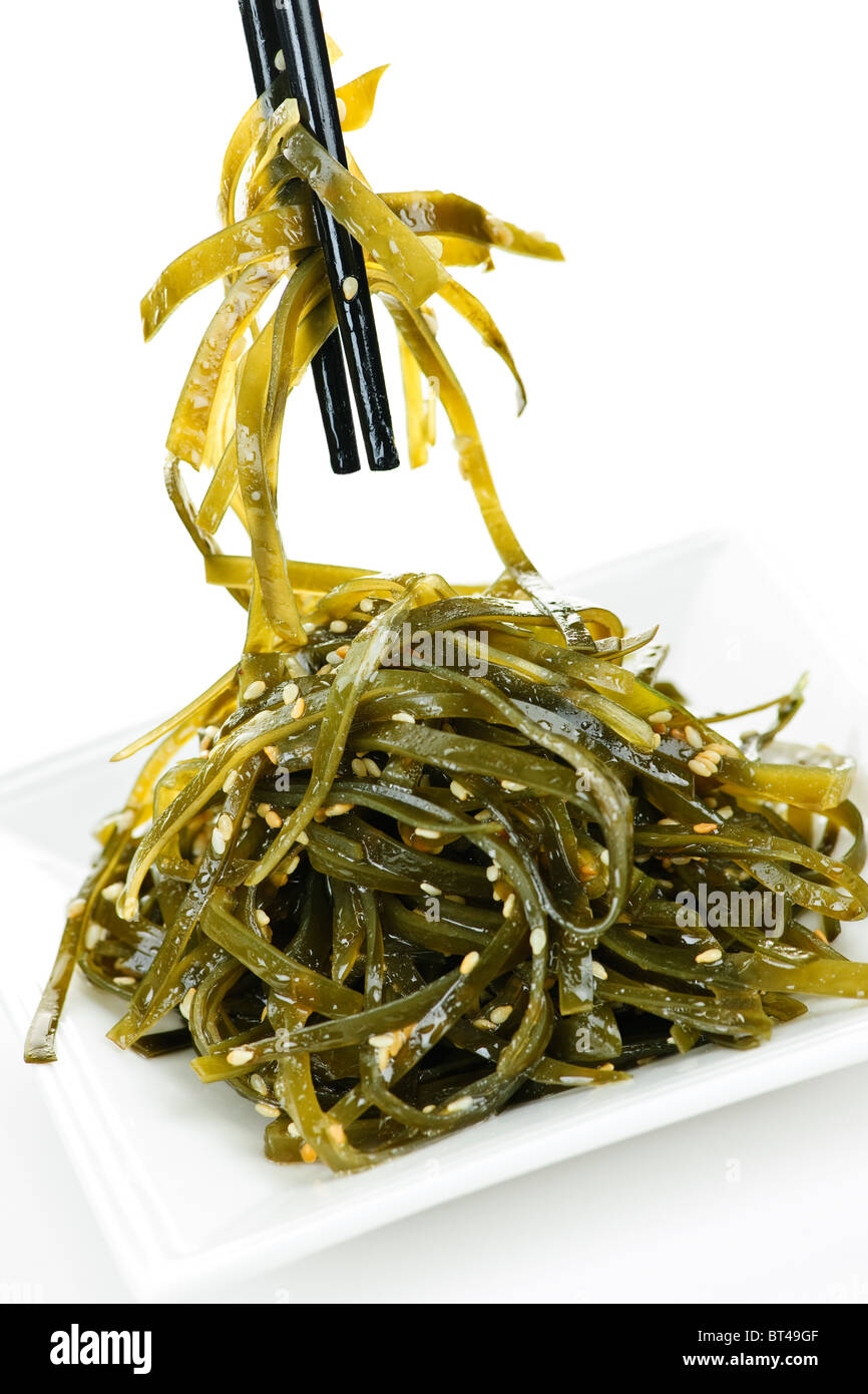 Plate of wakame seaweed salad with chopsticks on white background Stock Photo