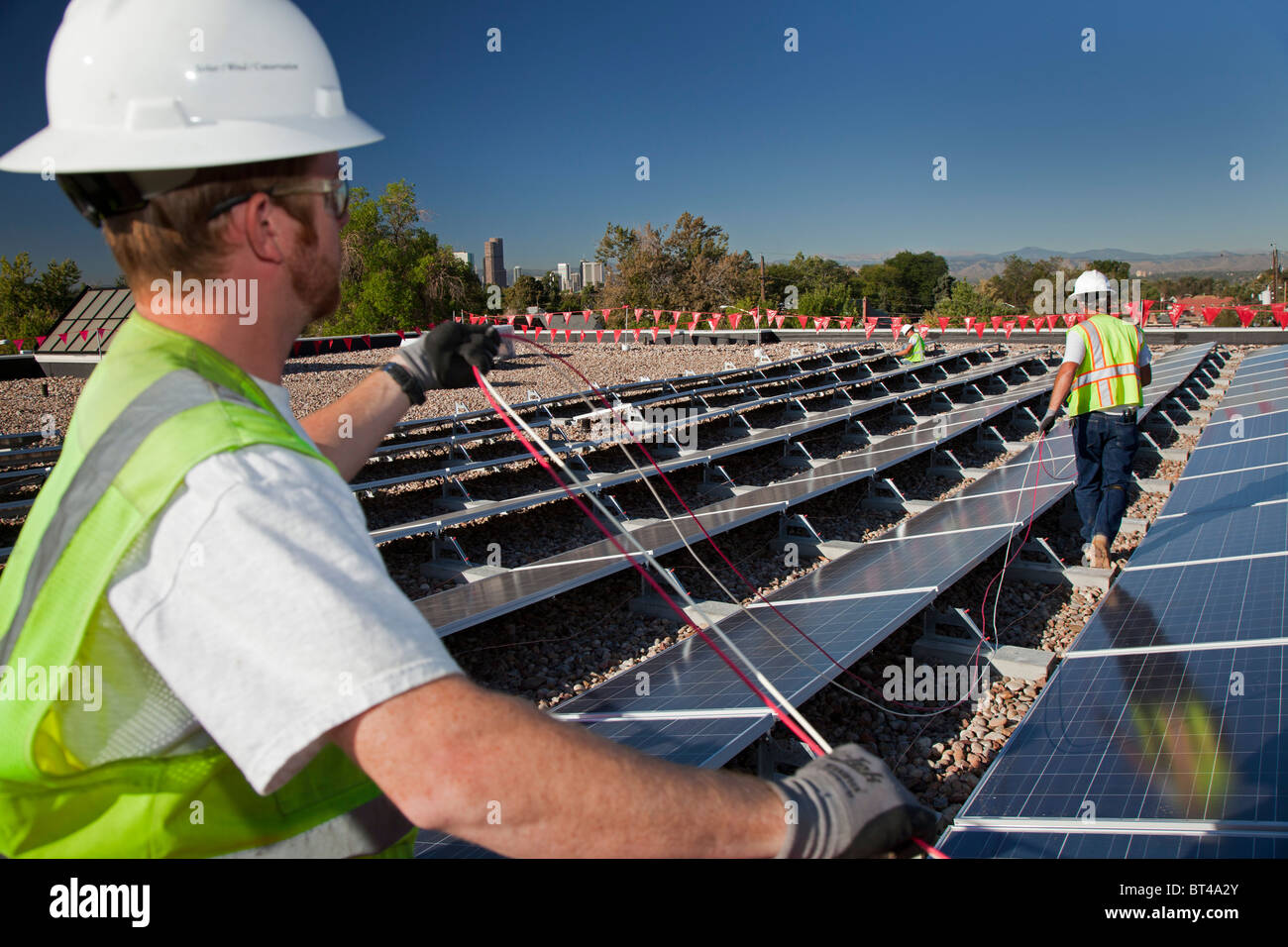 Denver, Colorado Workers install wiring for solar photovoltaic panels