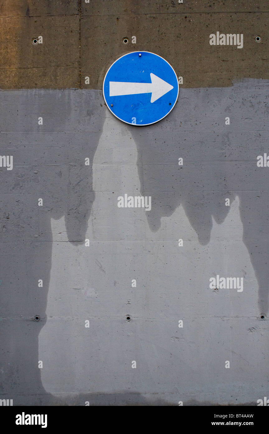 a blue and white arrow sign on a gray wall Stock Photo - Alamy