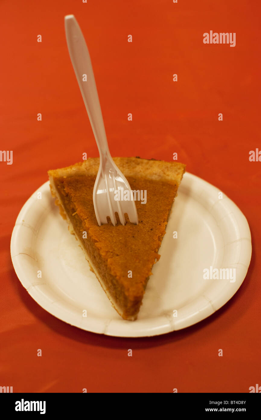 A slice of pumpkin pie on an orange tablecloth at a charity Thanksgiving dinner. Stock Photo