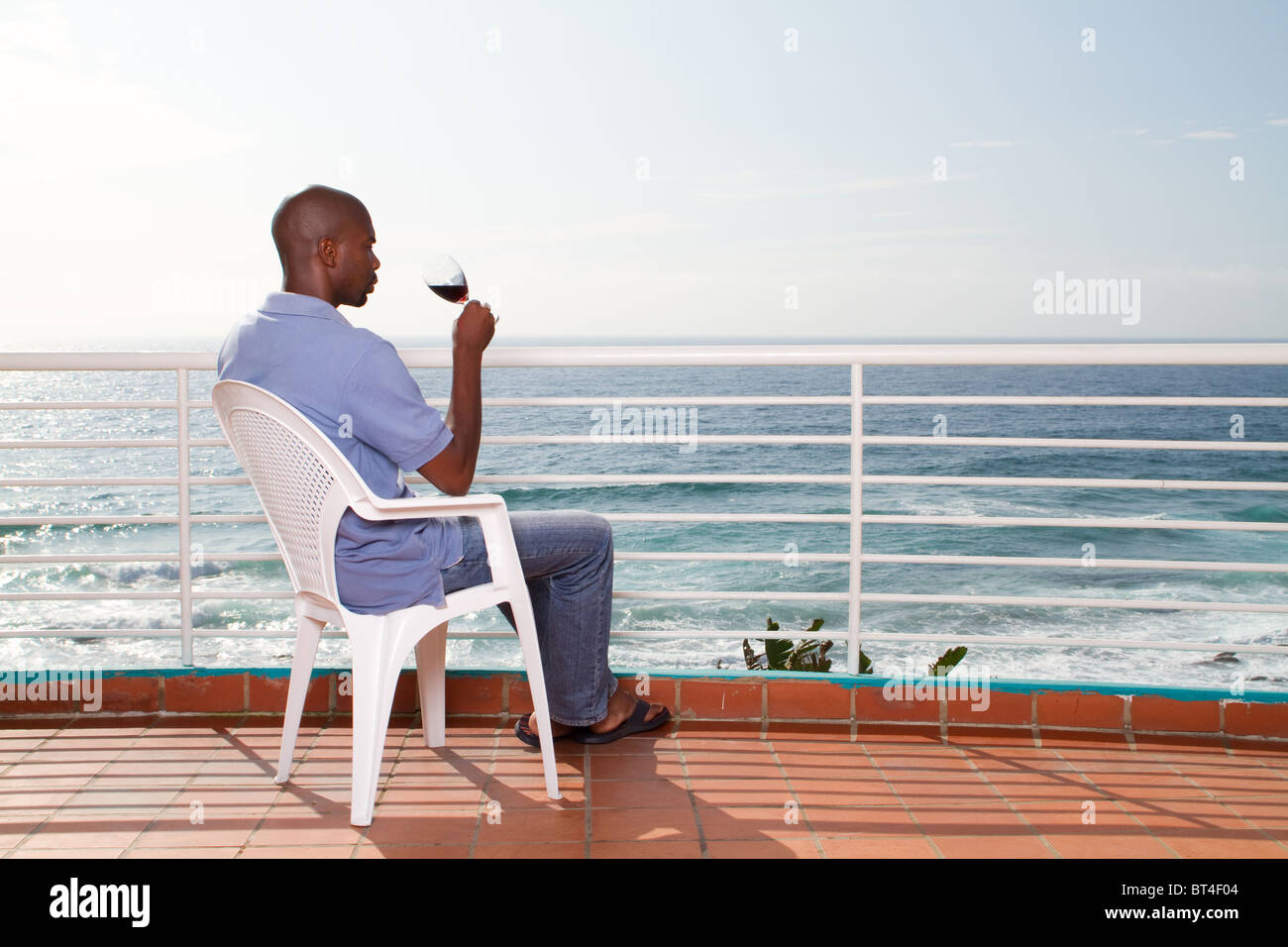 young african american man drinking wine on sea view balcony Stock ...