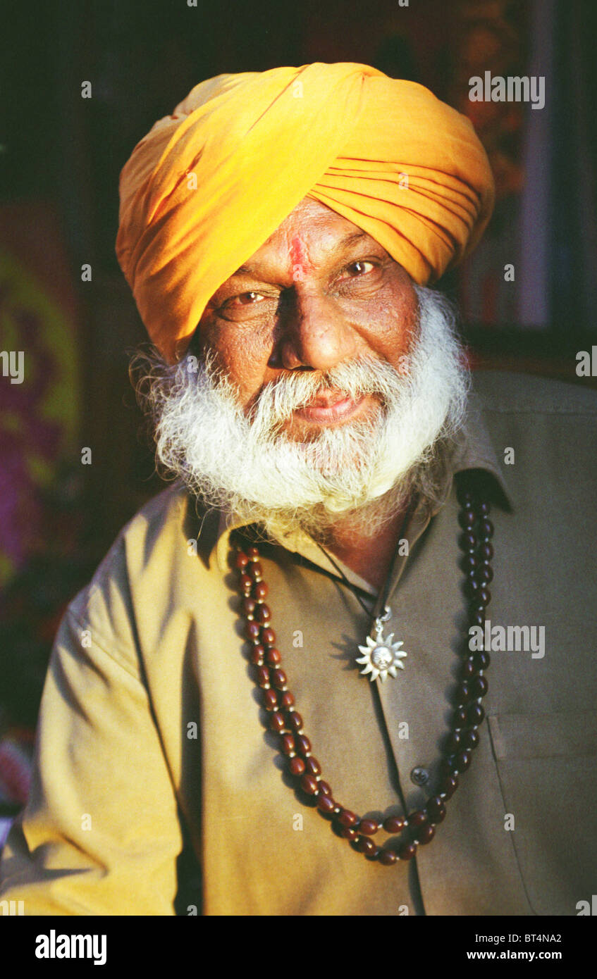 Indian man Portrait of an painter at market shop in Puskar Rajasthan India. wearing golden yellow turban. Stock Photo