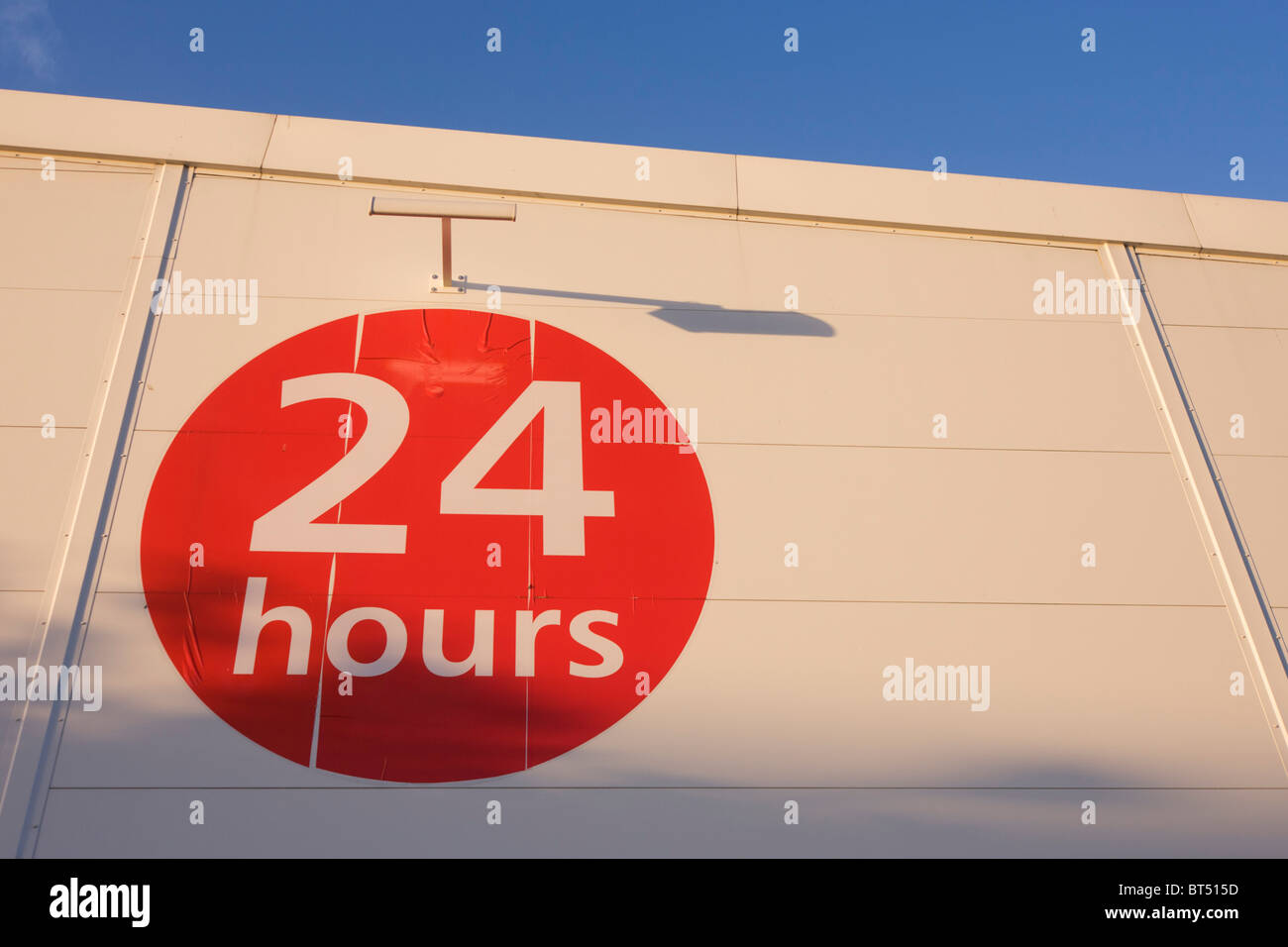 Red circular sign telling shoppers that supermarket is open 24 hours a