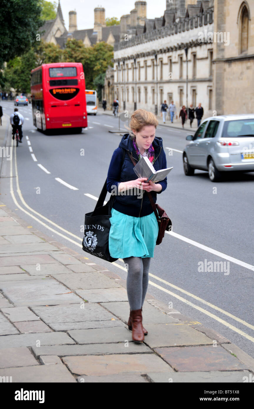 Student reading a book whilst walking over Magdalene Bridge, Oxford Stock Photo