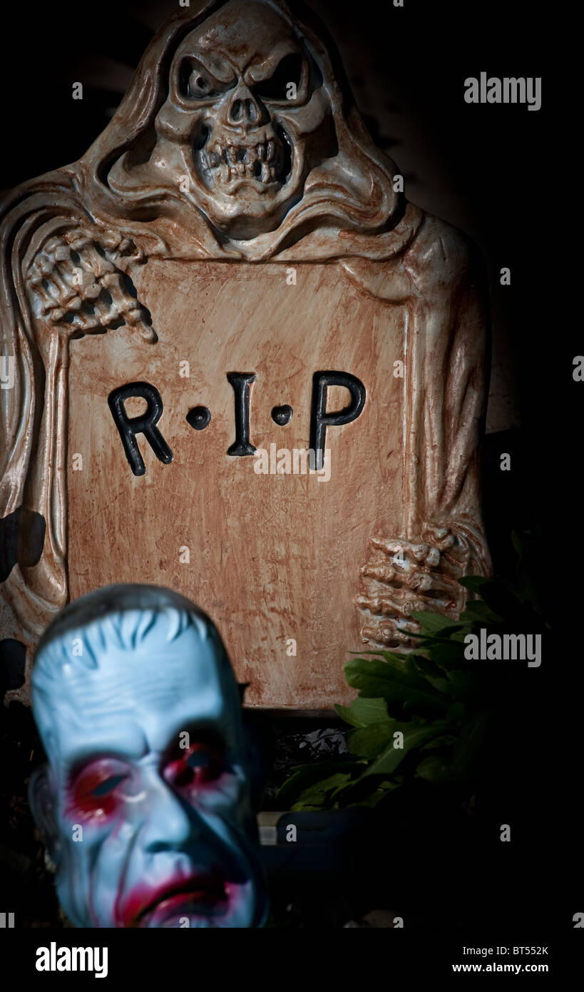 A halloween display with 'Rest in Peace' on the head stone, being held by a skull and bony fingers. Stock Photo