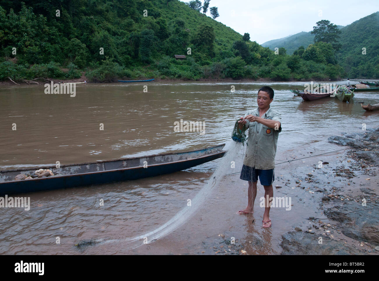 Fisherman folding his net at Nam Tha river bank. Kham Khone. Laos Stock Photo
