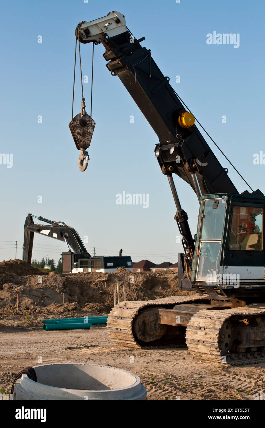 A mobile crane and a hydraulic excavator at a construction site Stock