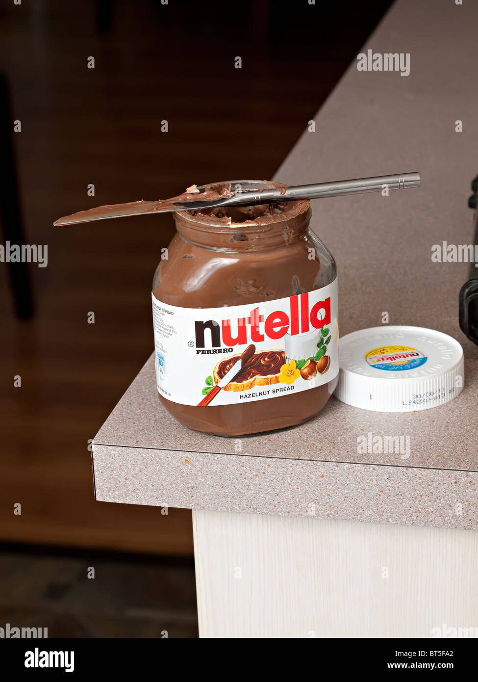 A box of Nutella on a kitchen bench with a smeraed knife Stock Photo