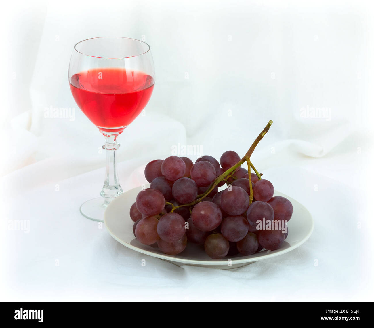 Still-life with a glass of red wine and grapes on a white background Stock Photo
