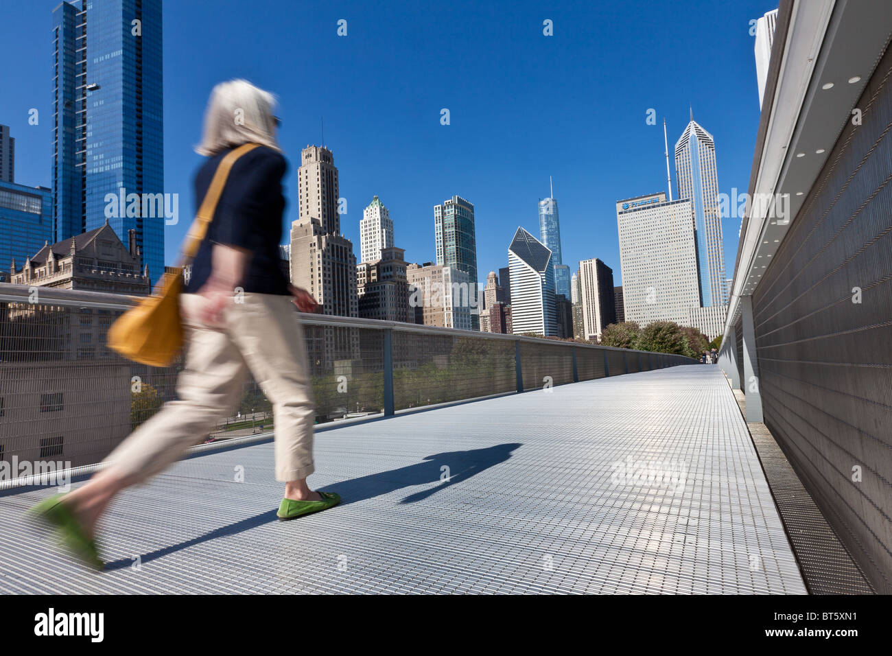 A pedestrian walks the Nichols Bridgeway with the Skyline of Chicago ...