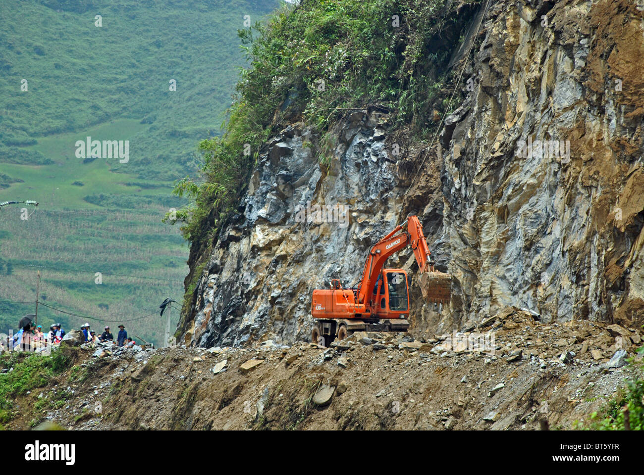 A digger clears rubble from a blocked road after landslides and rockfalls triggered by heavy rain in Sapa, Vietnam Stock Photo