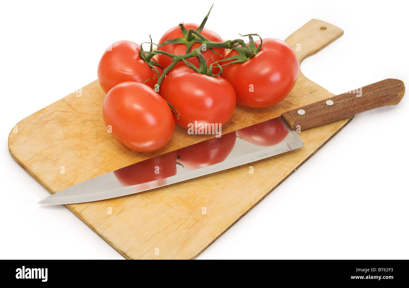 Knife and branch of tomatoes on a chopping board Stock Photo