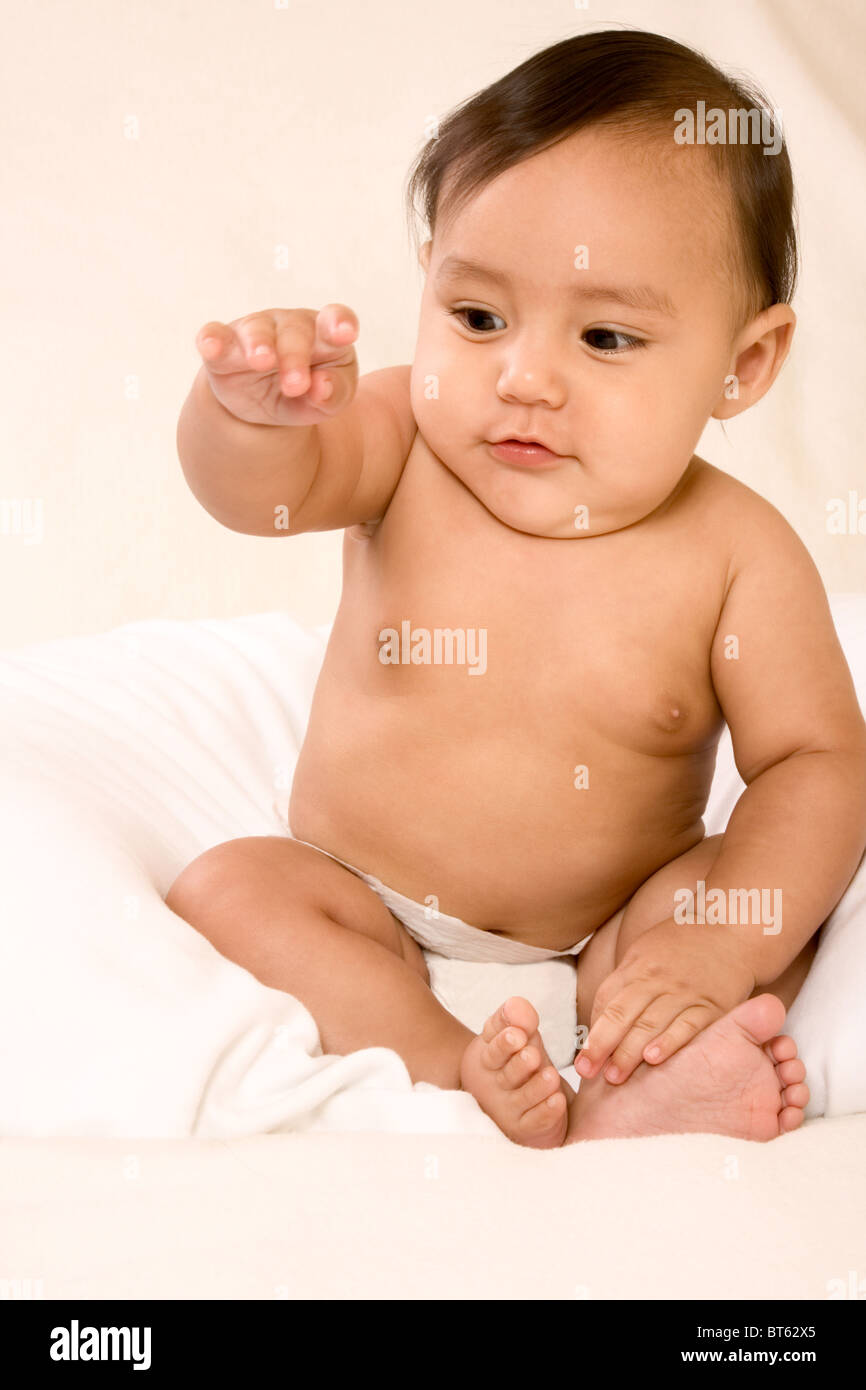 Asian infant sitting and pointing his finger out Stock Photo