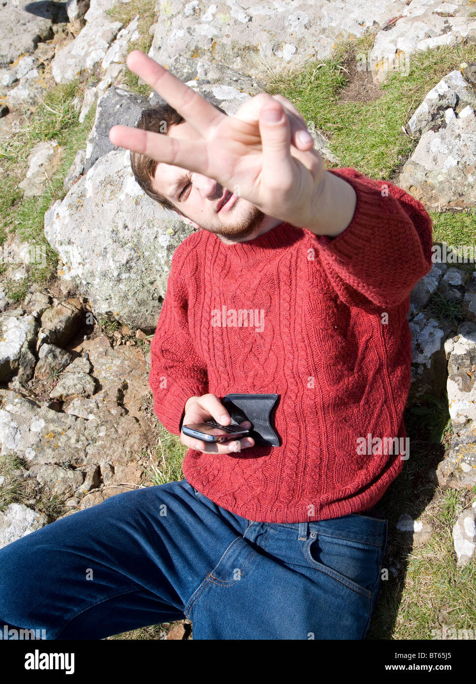 Young man making V peace sign with fingers Stock Photo