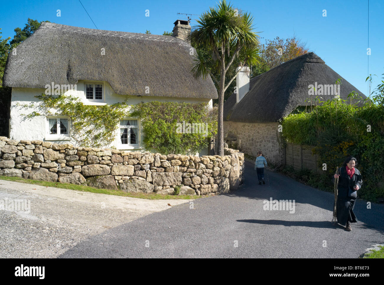 Walkers and thatched houses in the village of Pethybridge dartmoor