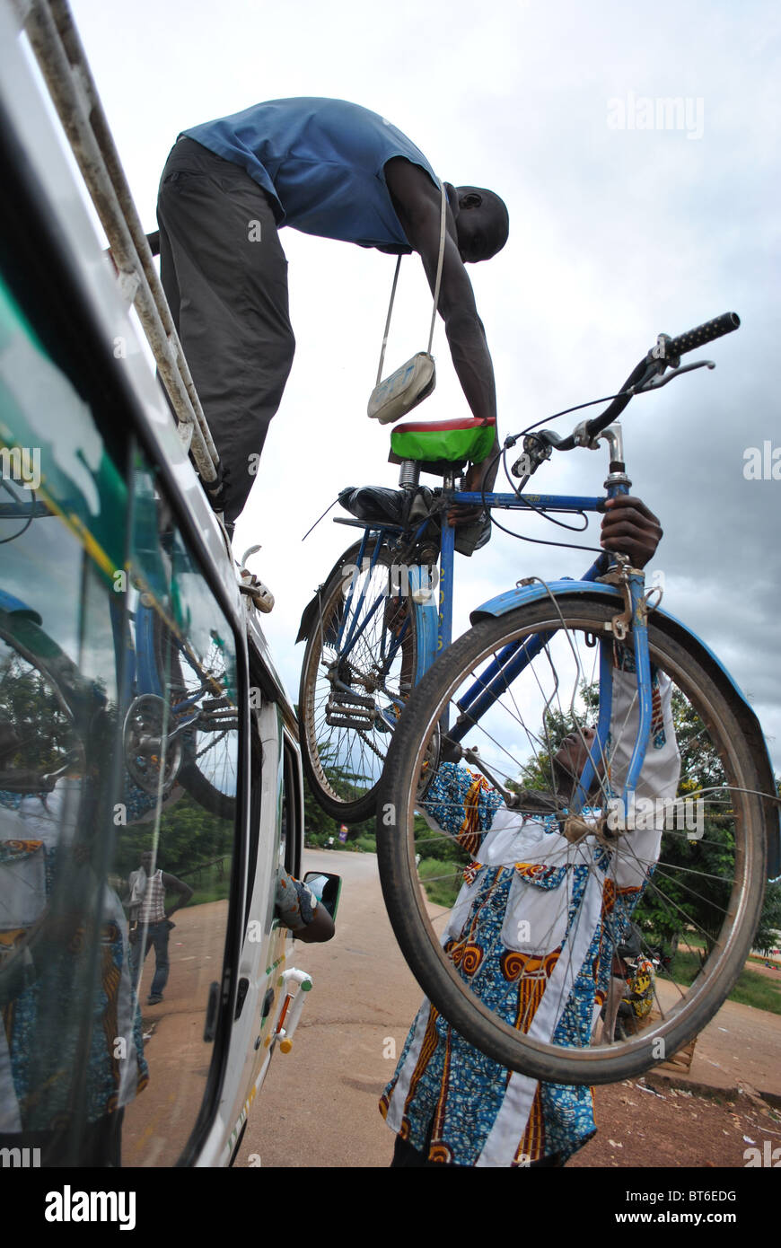 People loading a bicylcle onto the roof of a bush-taxi in Ivory Coast, West Africa Stock Photo