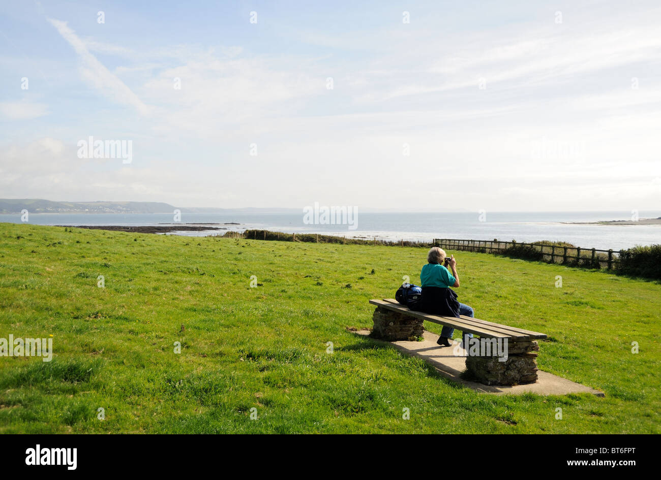Woman relaxing on a bench on a coastal path Stock Photo