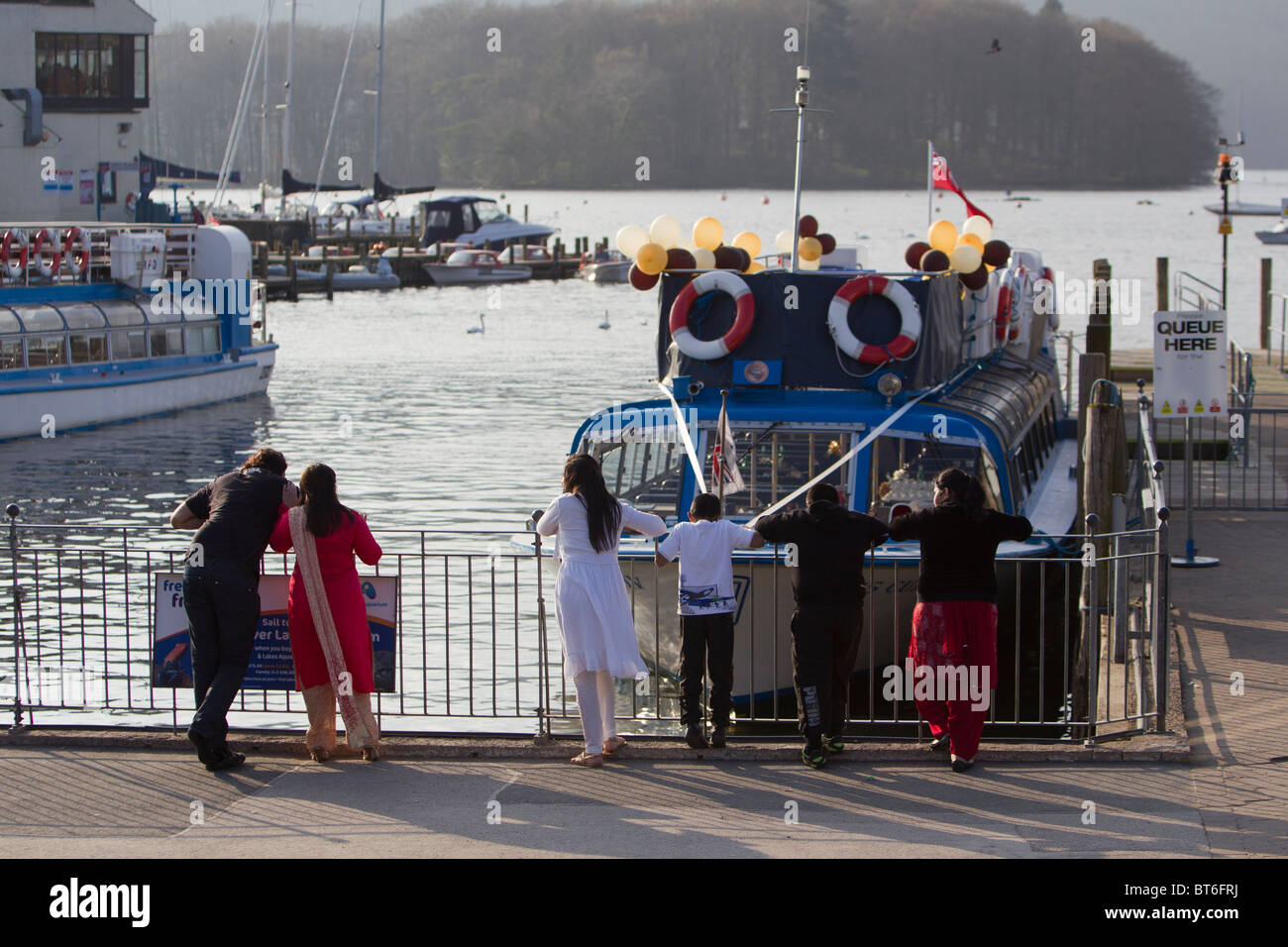 Asian  dressed tourists in Bowness on Windermere on Lake Windermere Lake District Stock Photo