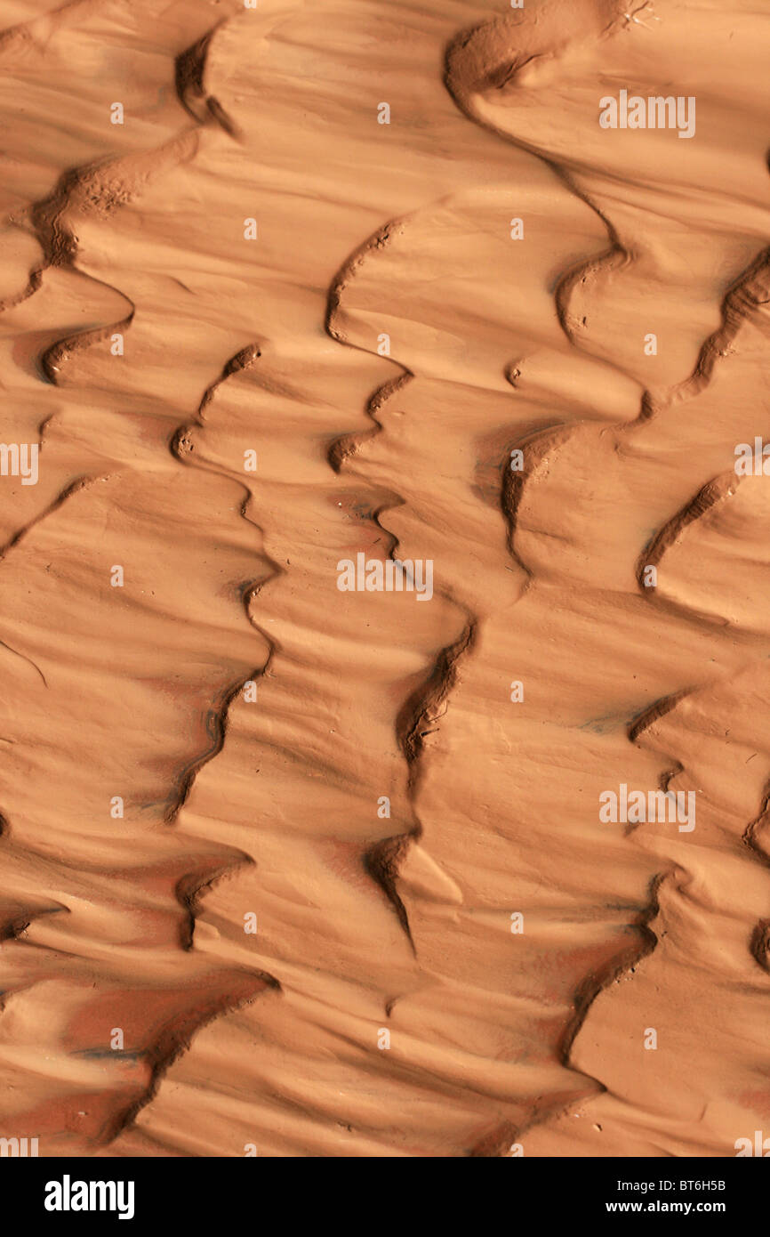 vertical image of reddish sand and mud ripples caused by flowing water Stock Photo