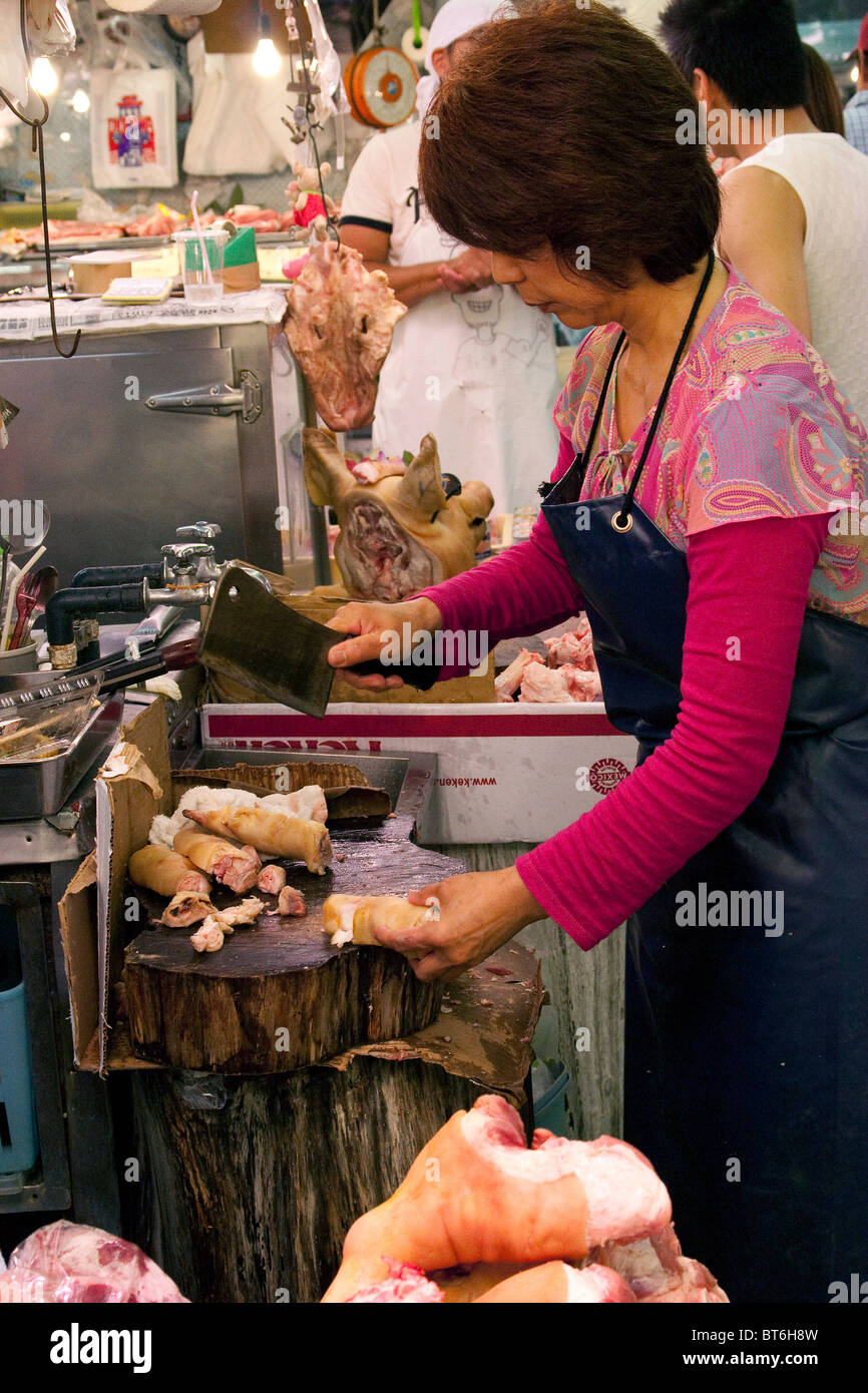 Japanese woman chopping pig feet at Makishi Market at Heiwa-Dori, Naha City in Okinawa Japan Stock Photo