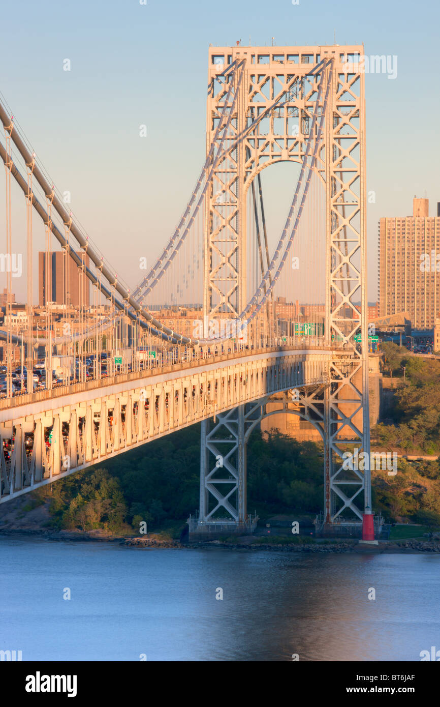 The George Washington Bridge and evening traffic high over Jeffrey's Hook Lighthouse on the Hudson River Stock Photo