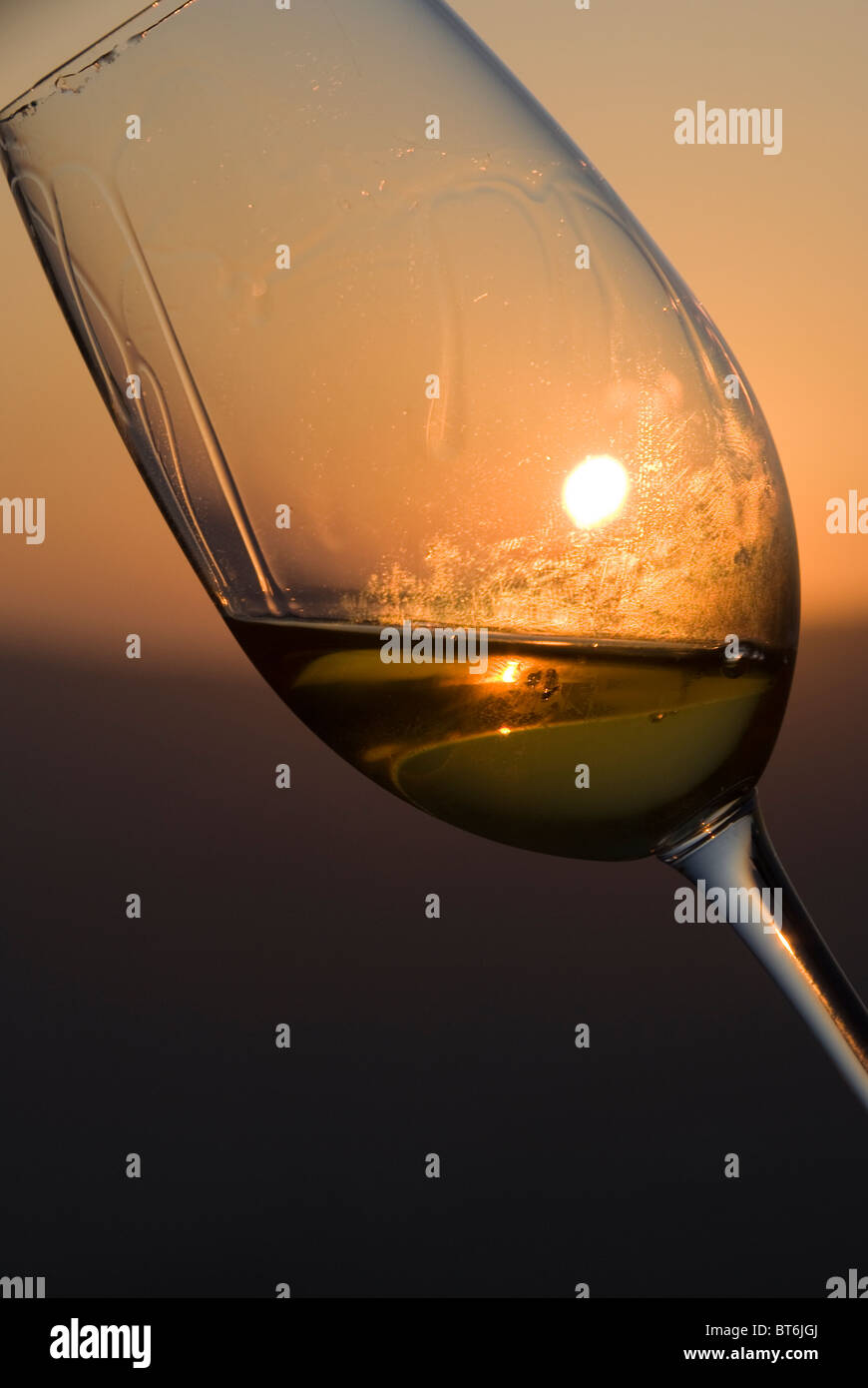 White wine glass in front of the sunset horizon. Stock Photo