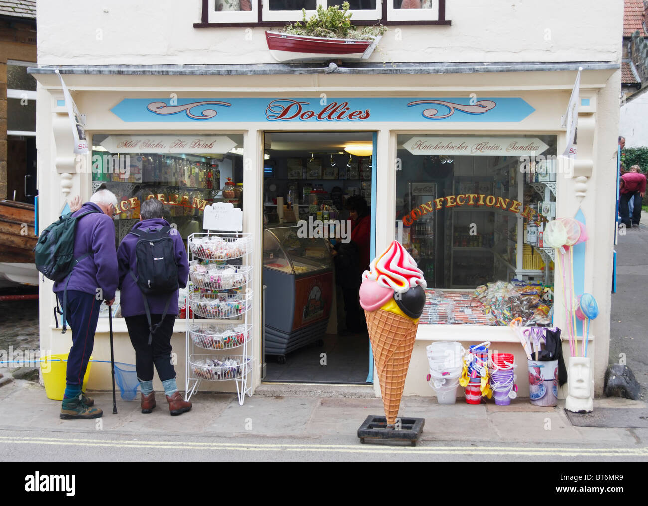 Mature couple in walking gear outside Dollies sweets and confectionery shop in Robin Hoods Bay