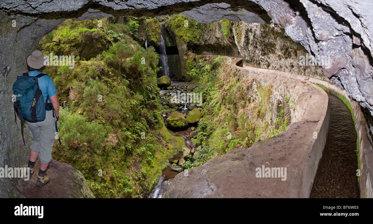 Hiker looking at the waterfall on Levada Nova from a tunnel, Lombada da Ponta do Sol, Madeira, Portugal Stock Photo