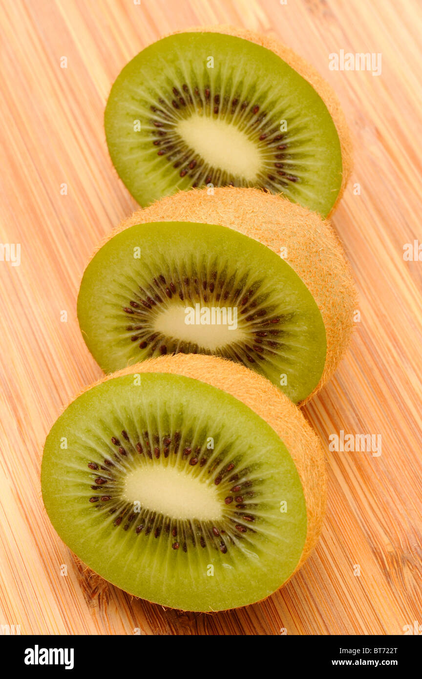 Kiwi (Actinidia deliciosa), cut in half on a wooden board Stock Photo