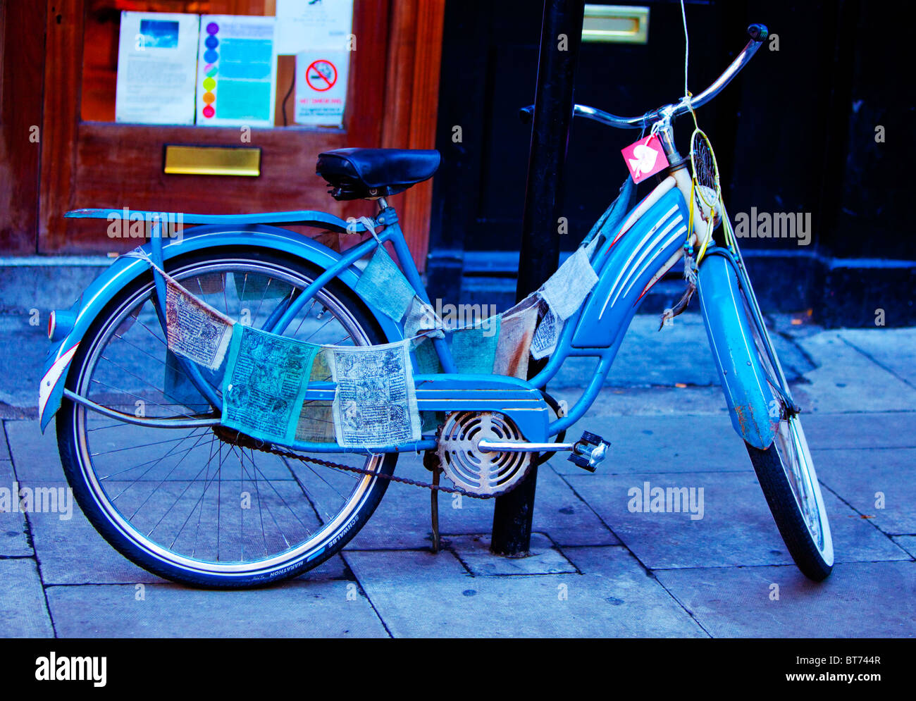 A blue bicycle propped up against a pole on a pavement, London, England, UK. Stock Photo