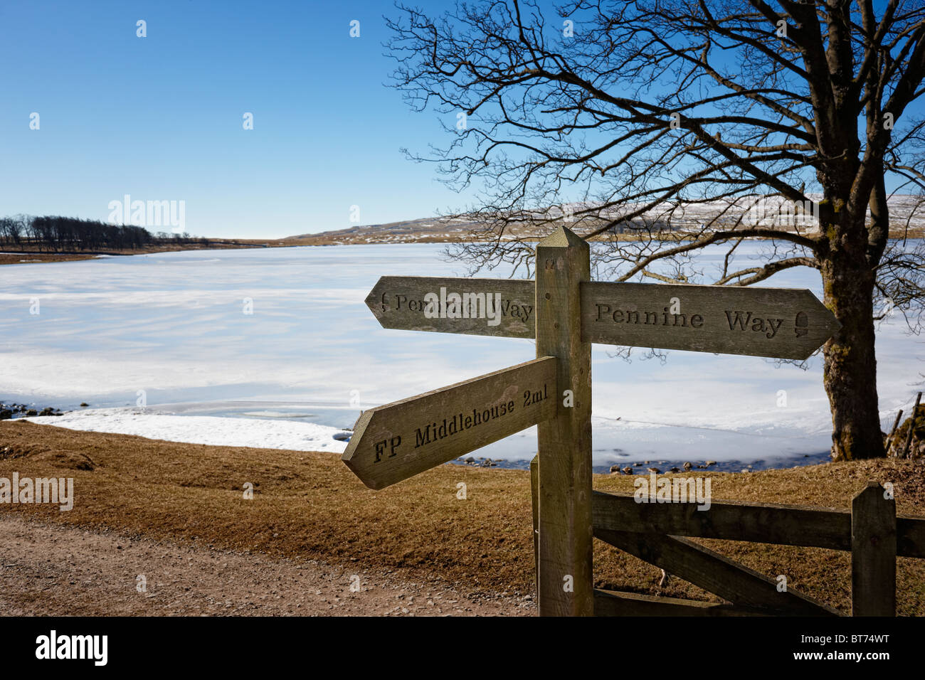 Pennine Way signpost by a frozen Malham Tarn, North Yorkshire Stock Photo