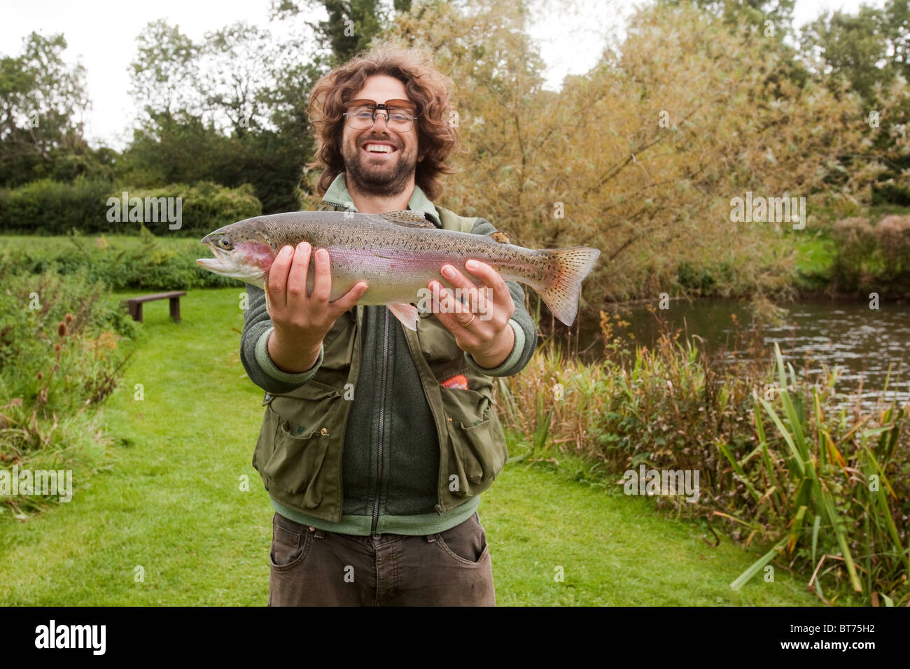 Fly Fisherman with a rainbow trout fish, Moorhen trout fishery , Warnford, Hampshire, England, United Kingdom. Stock Photo